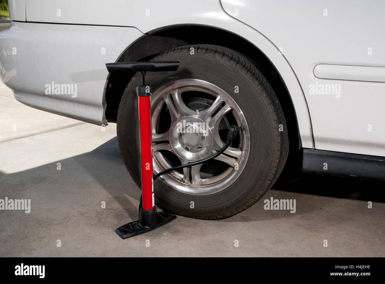 Car tire with bicycle pump hooked up to it Stock Photo