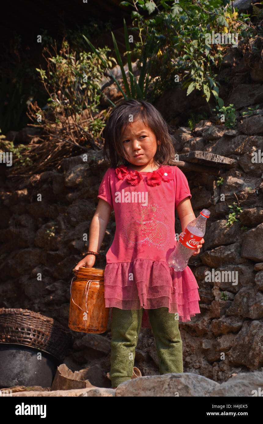 A small girl holds an empty Coke bottle near the village of Jallesoy, Solukhumbu, Nepal Stock Photo