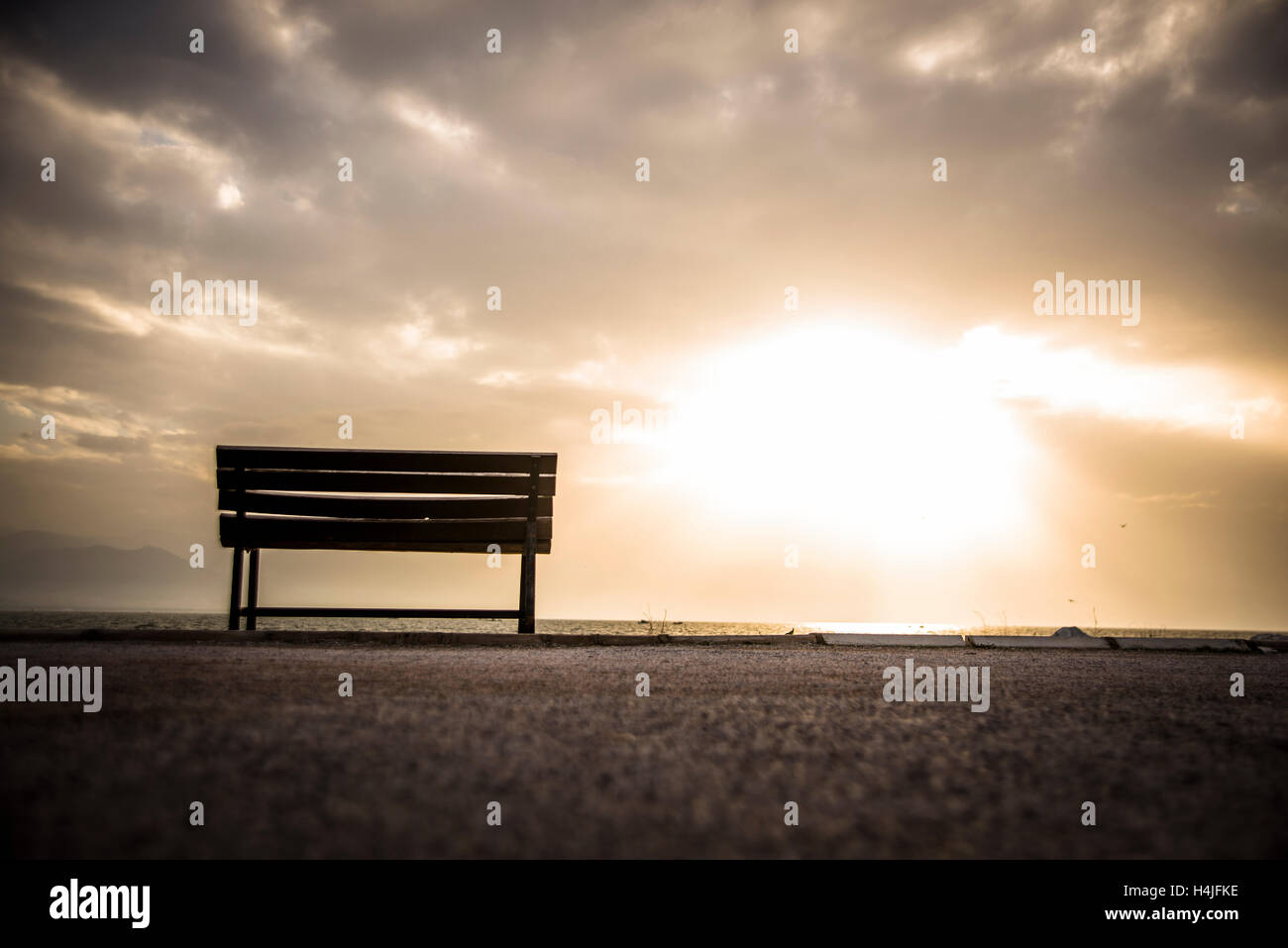 An empty bench set against a sunset sky. Stock Photo