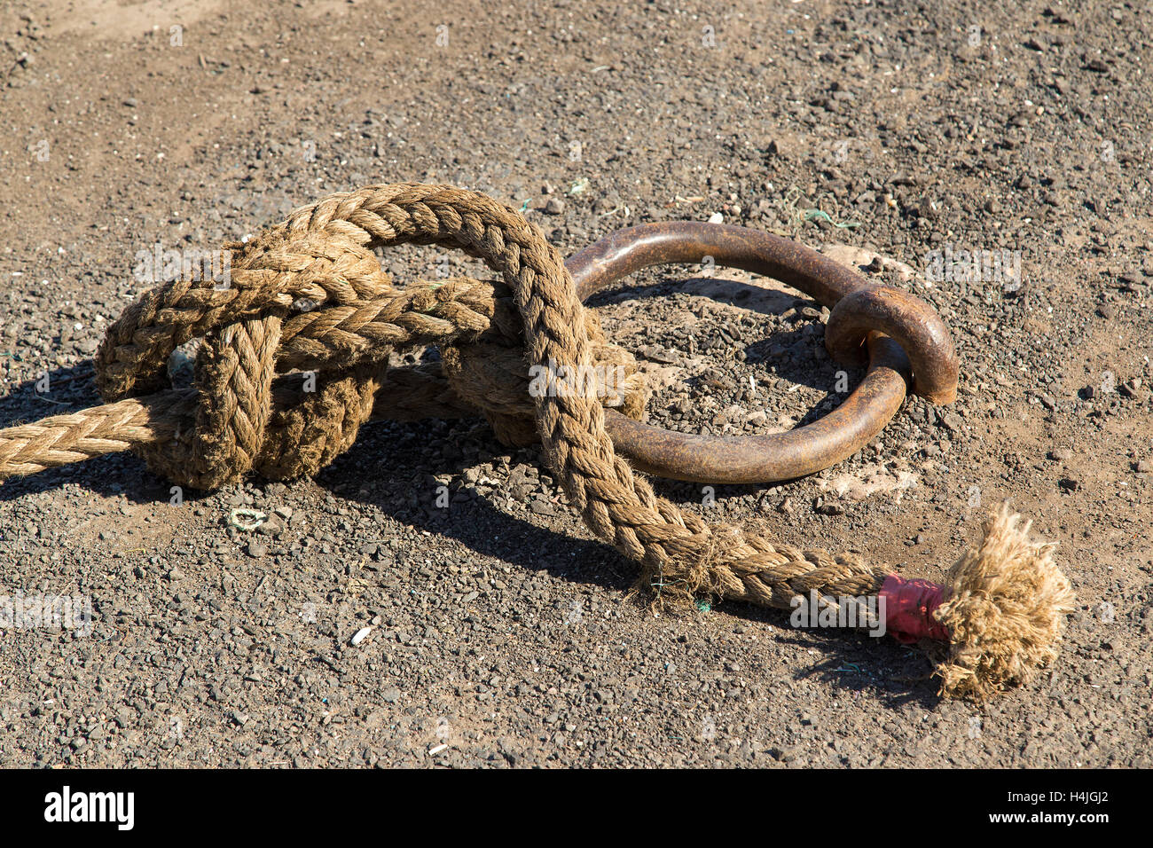 Close up of ship's hemp rope knotted around mooring ring, bowline knot. Stock Photo