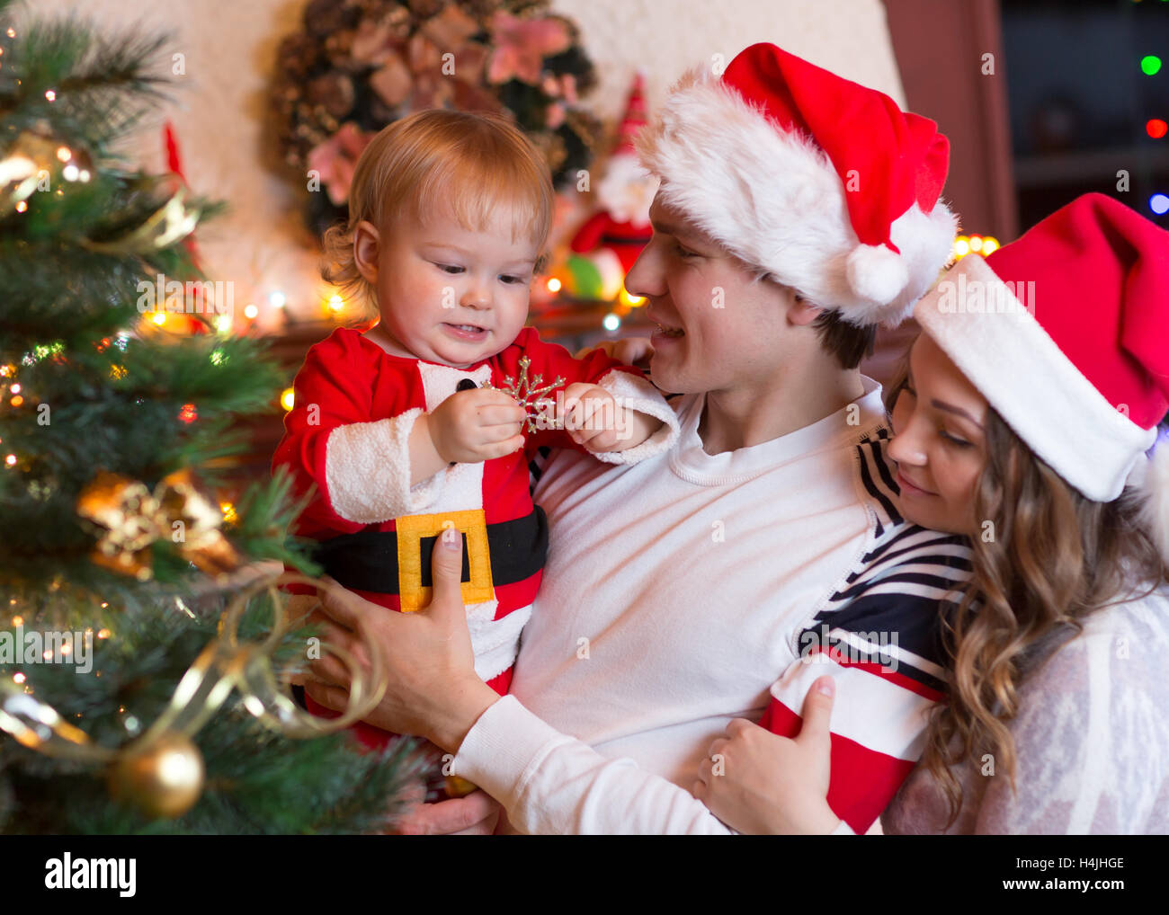 Happy mother and father with baby near Christmas tree Stock Photo