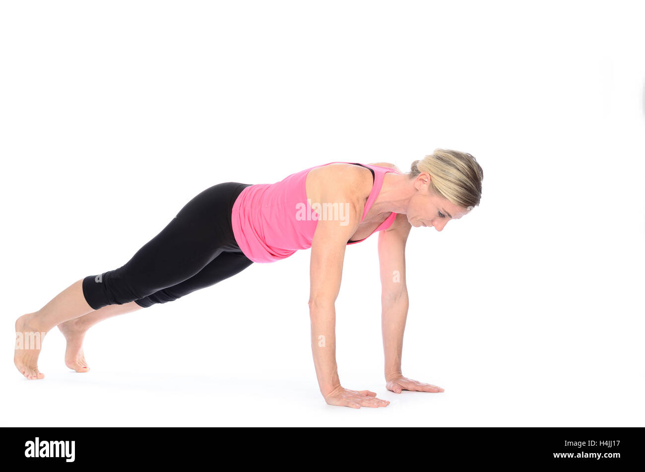 Healthy fit woman working out doing press-ups and balancing on her hands and toes isolated on white with copy space Stock Photo