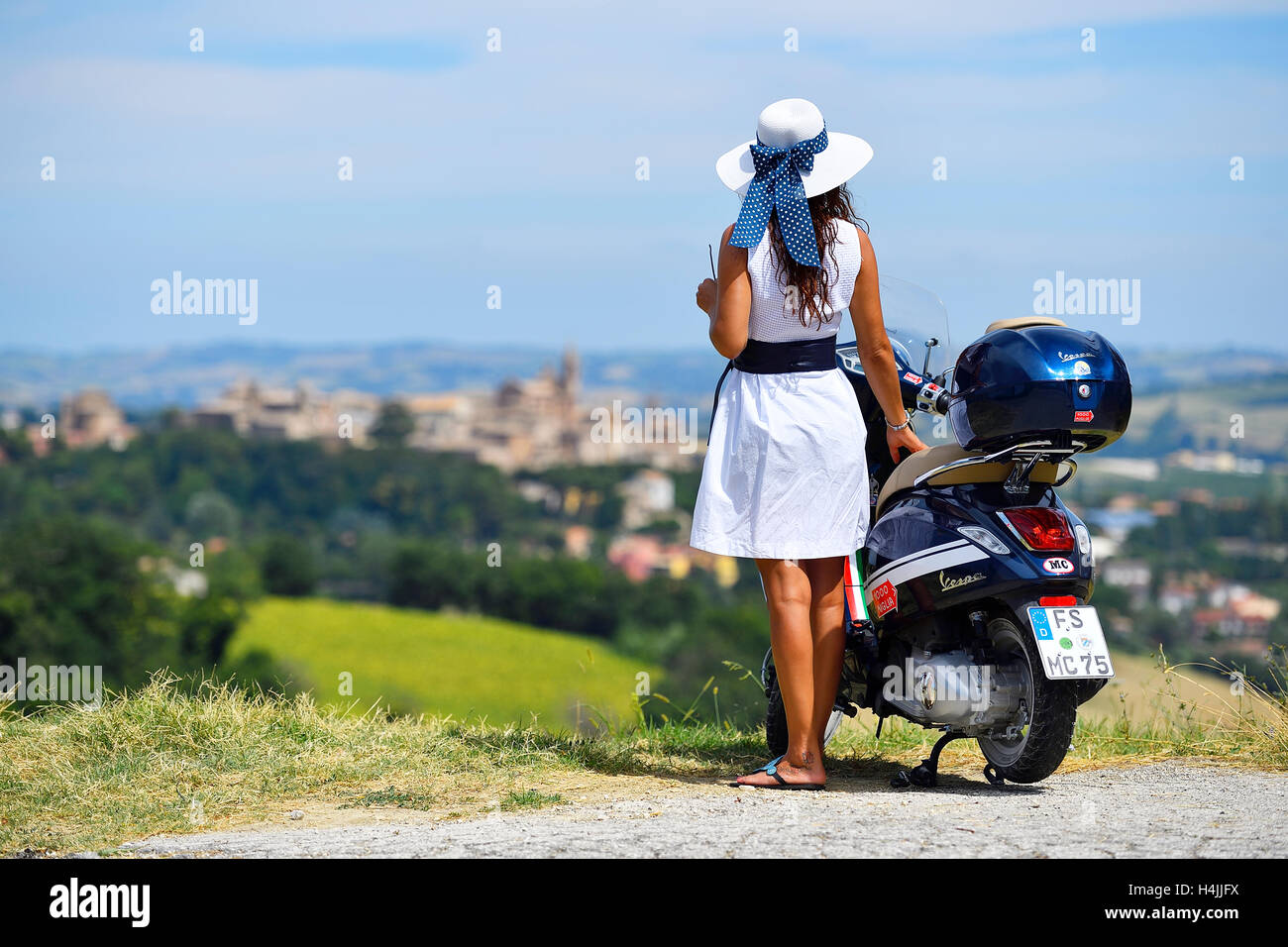 Woman with white sunhat next to Vespa Primavera scooter, Corinaldo, Marche, Italy Stock Photo