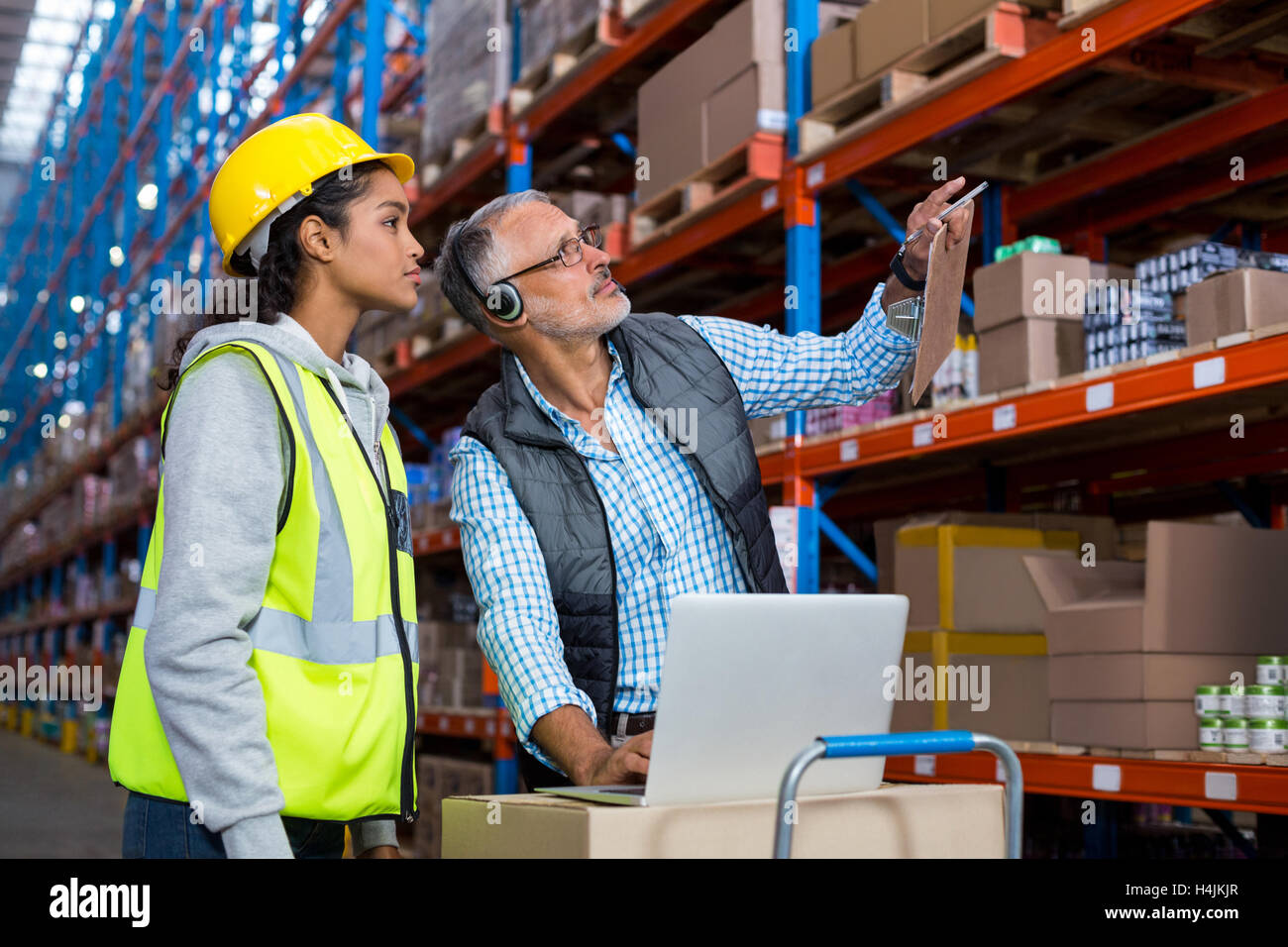 Warehouse manager and female worker interacting while using laptop Stock Photo