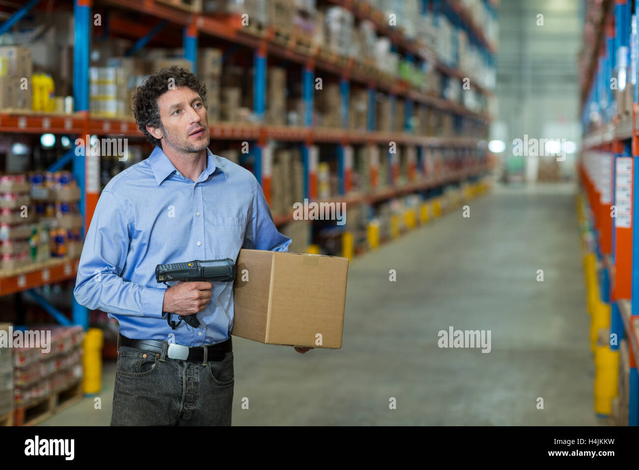 Warehouse worker holding cardboard box and barcode scanner machine Stock Photo