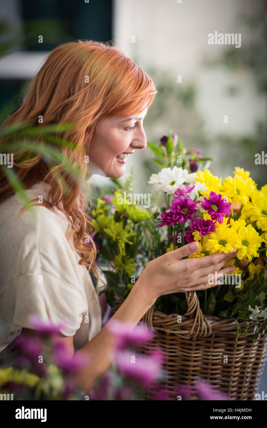 Happy female florist holding basket of flowers Stock Photo
