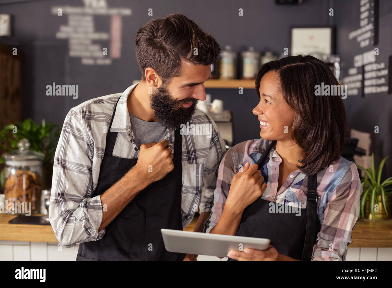 Smiling waiter and waitress interacting while using digital tablet Stock Photo