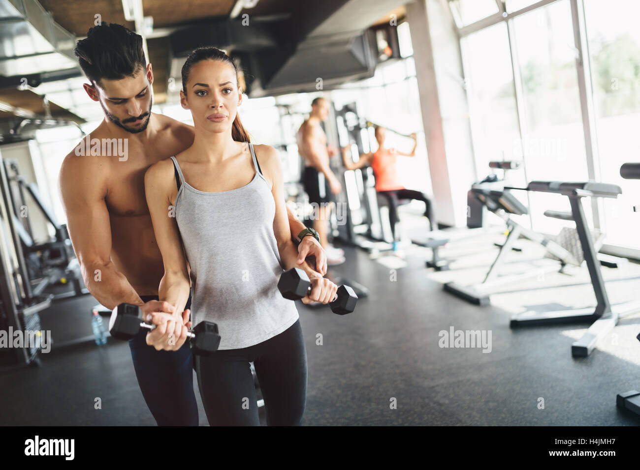 Personal trainer helping woman in gym Stock Photo - Alamy