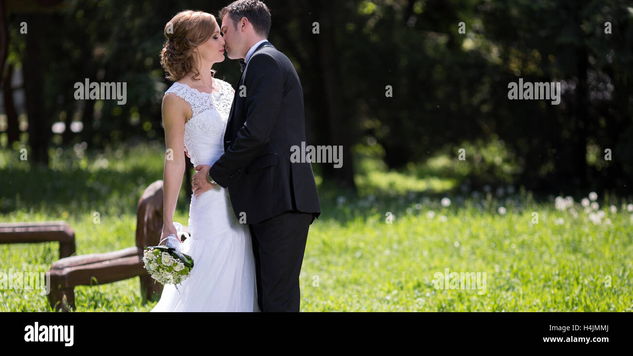 Beautiful bride and groom kissing outdoors Stock Photo - Alamy