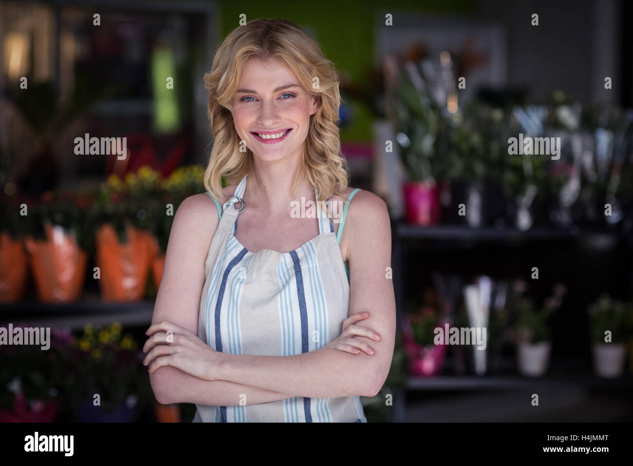 Happy female florist standing with arms crossed in flower shop Stock Photo