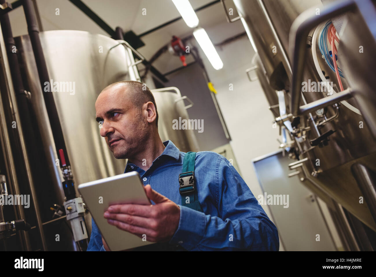 Manufacturer with digital tablet examining machinery Stock Photo