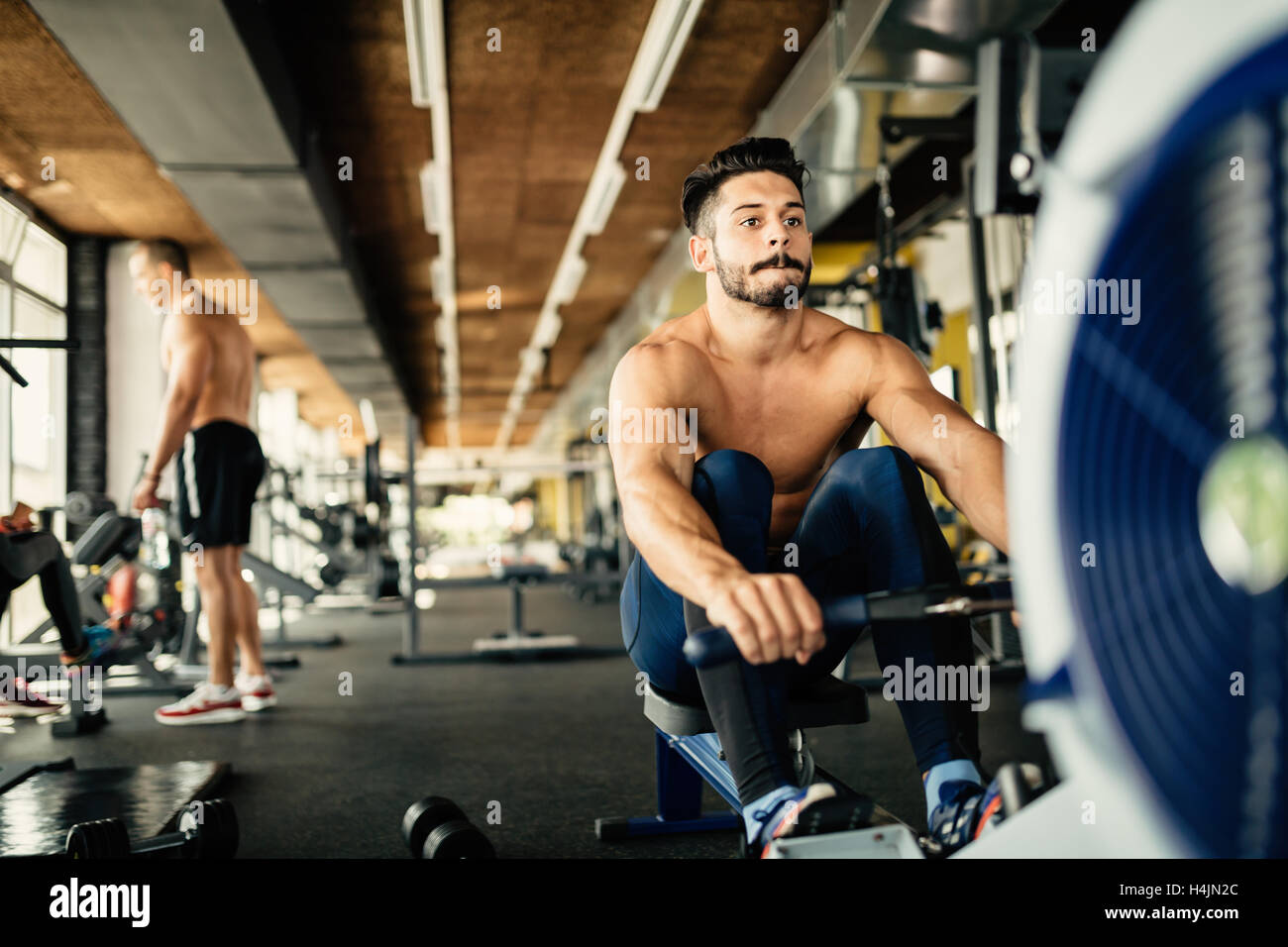 Determined bodybuilder rowing in gym Stock Photo