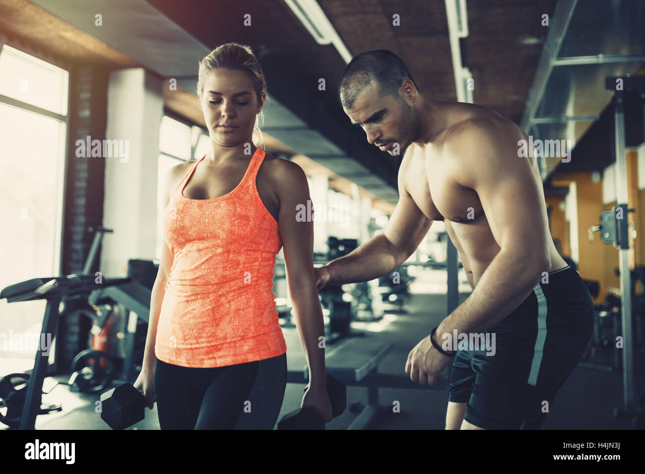 Personal trainer helping woman in gym Stock Photo - Alamy