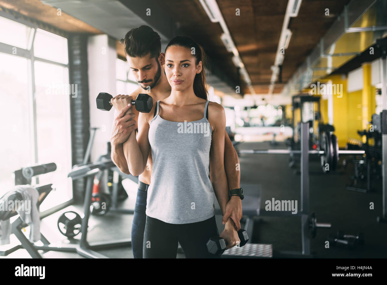 Personal trainer helping woman in gym Stock Photo - Alamy