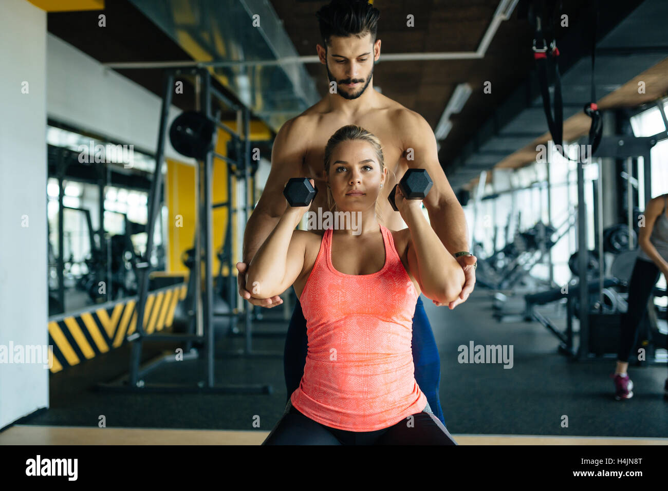 Personal trainer helping woman in gym Stock Photo - Alamy