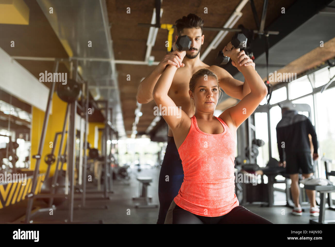 Personal trainer helping woman in gym Stock Photo - Alamy