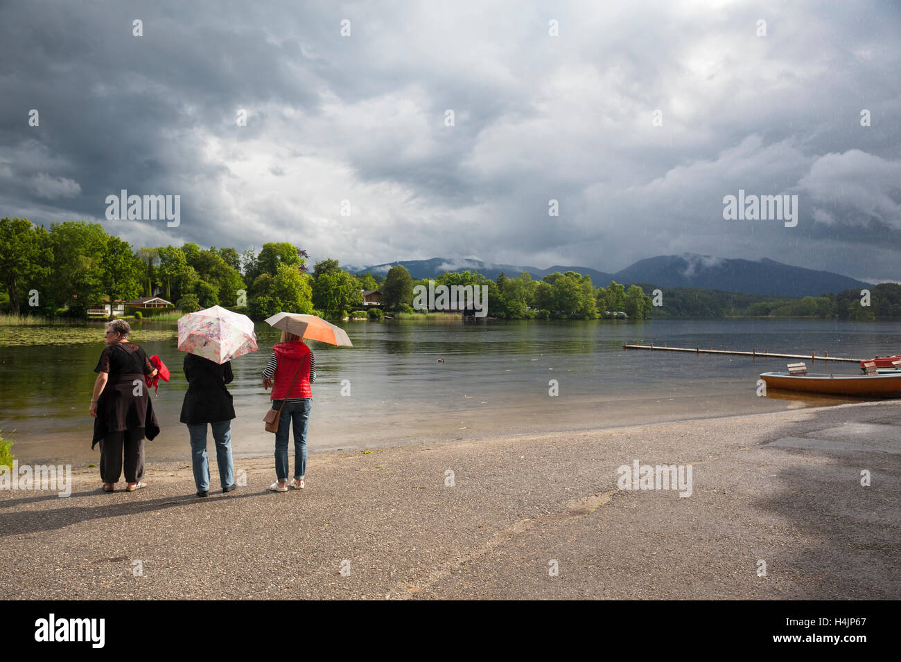 Rear view of three women, two of them sheltering under a umbrella. Staffelsee. Upper Bavaria. Germany. Stock Photo