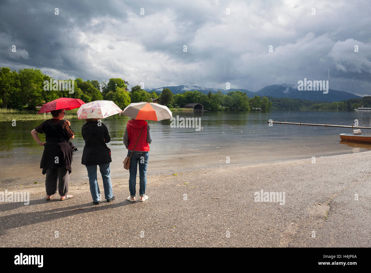Rear view of three women sheltering under a umbrella. Staffelsee. Upper Bavaria. Germany. Stock Photo