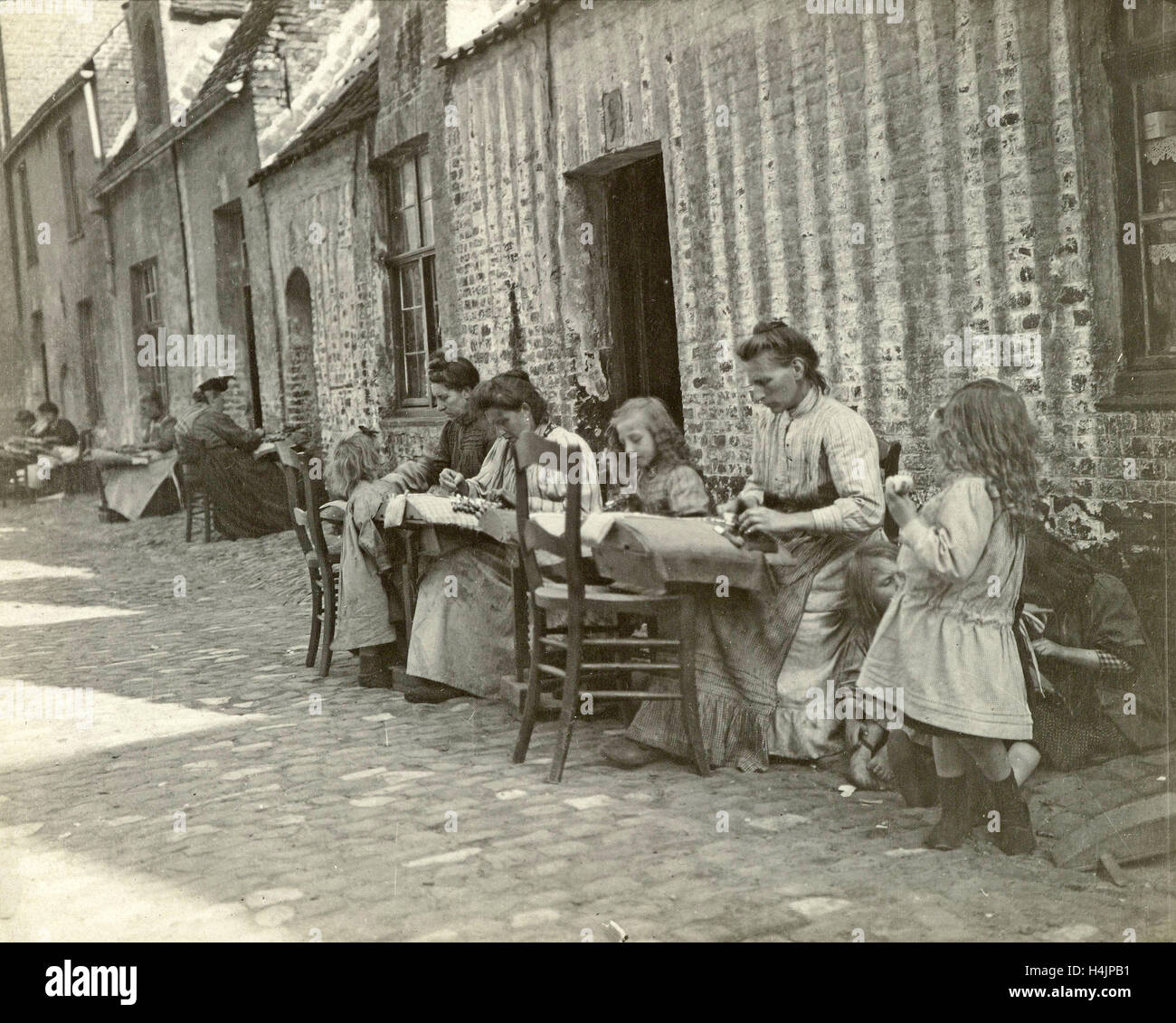 Street and women lacemaking, Anonymous, c. 1900 Stock Photo