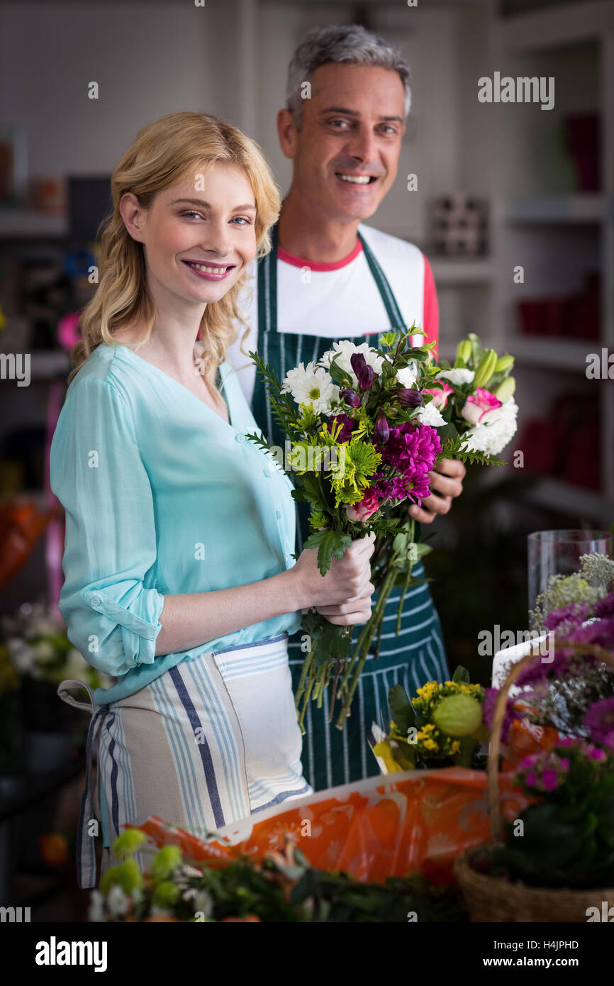 Smiling florists holding bunch of flowers in flower shop Stock Photo