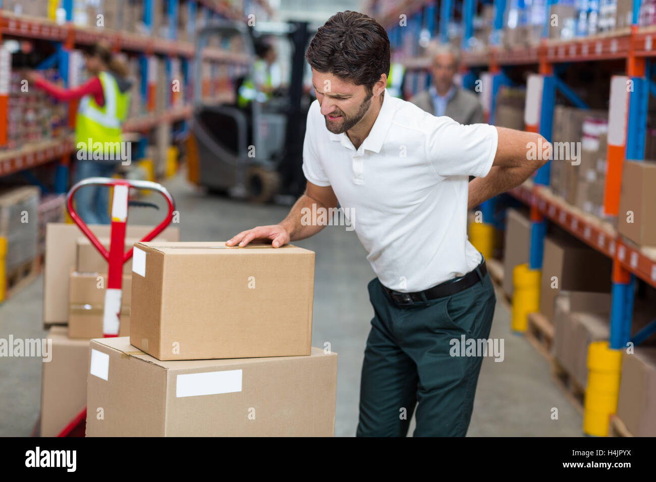 Male worker suffering from back pain while working Stock Photo