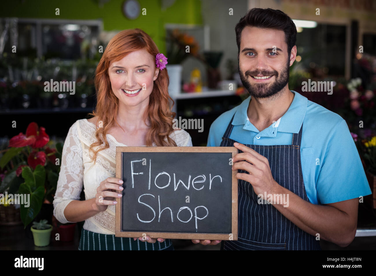 Portrait of couple holding slate with flower shop sign Stock Photo