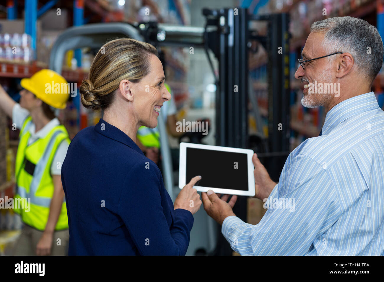 Warehouse manager and client discussing over digital tablet Stock Photo