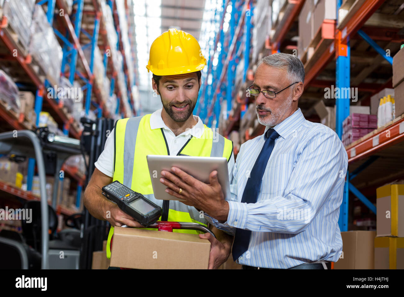 Warehouse manager with interacting male worker over digital tablet Stock Photo
