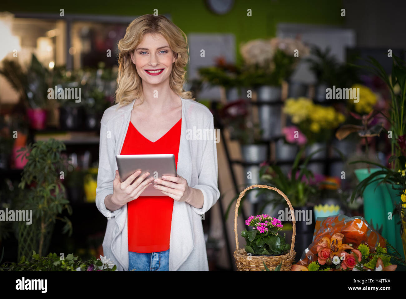 Happy female florist holding digital tablet in flower shop Stock Photo