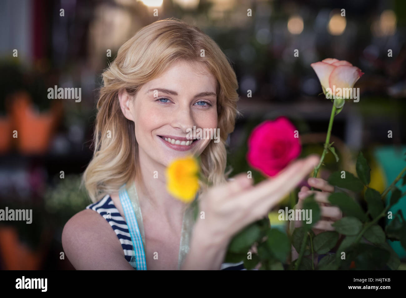 Smiling female florist arranging flower bouquet in vase at flower shop Stock Photo