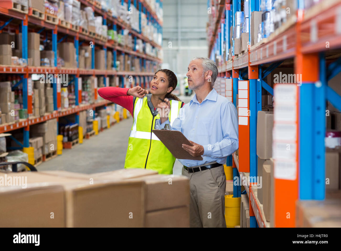 Warehouse manager and female worker interacting while checking inventory Stock Photo