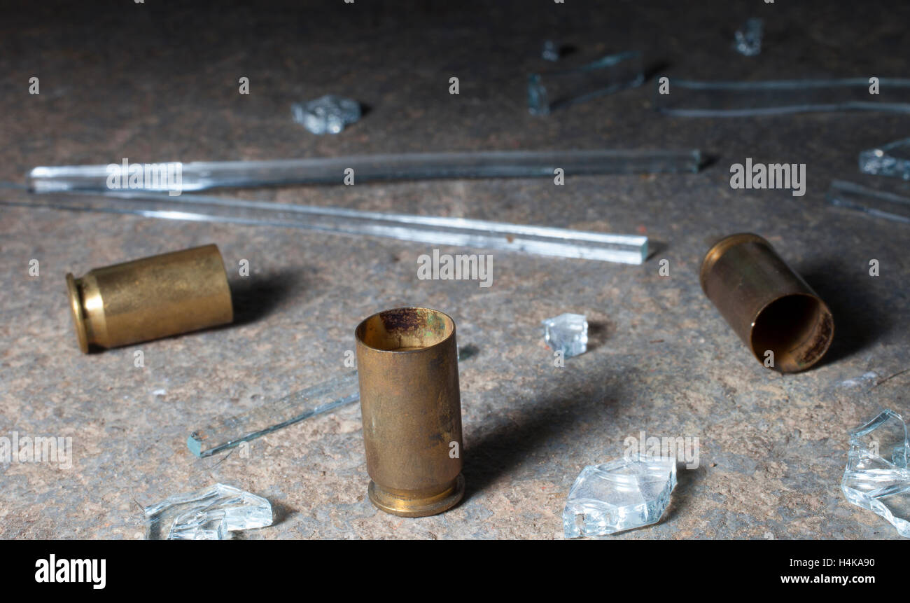 Empty handgun shells on concrete with broken glass around Stock Photo