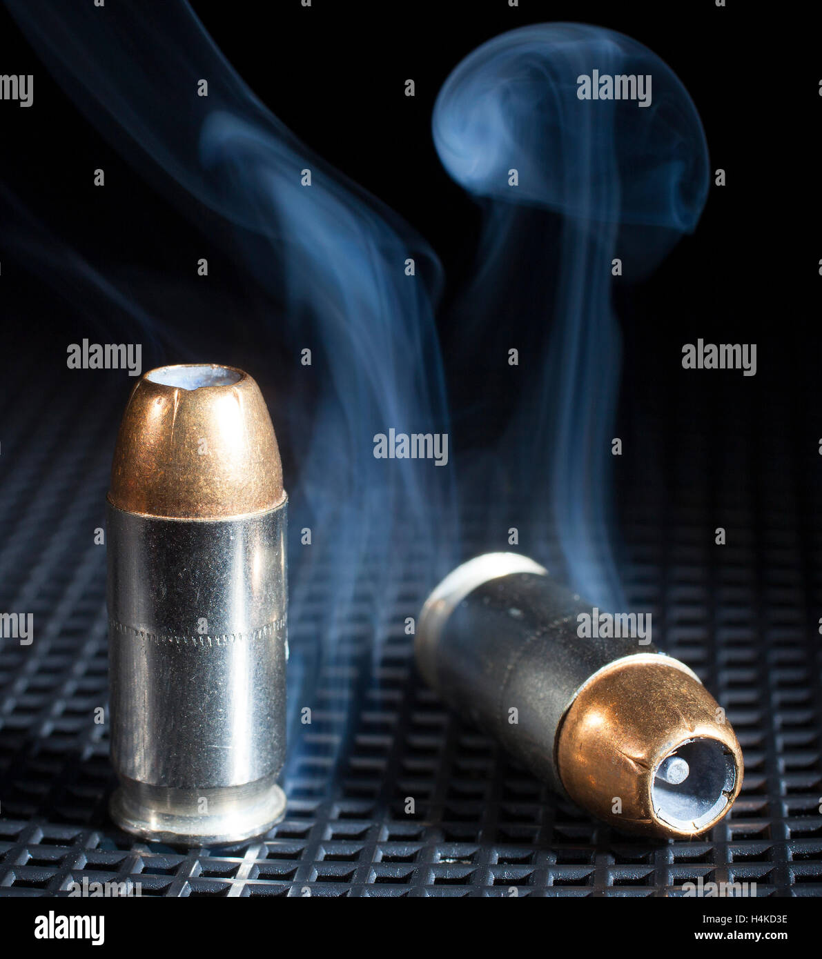Two bullets with hollow points that are surrounded by smoke Stock Photo