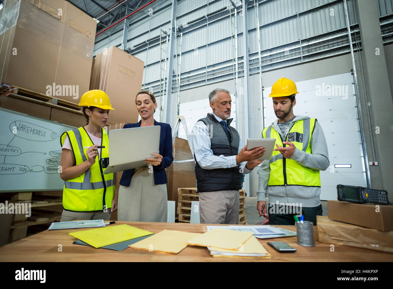 Warehouse managers and workers discussing with laptop and digital tablet Stock Photo