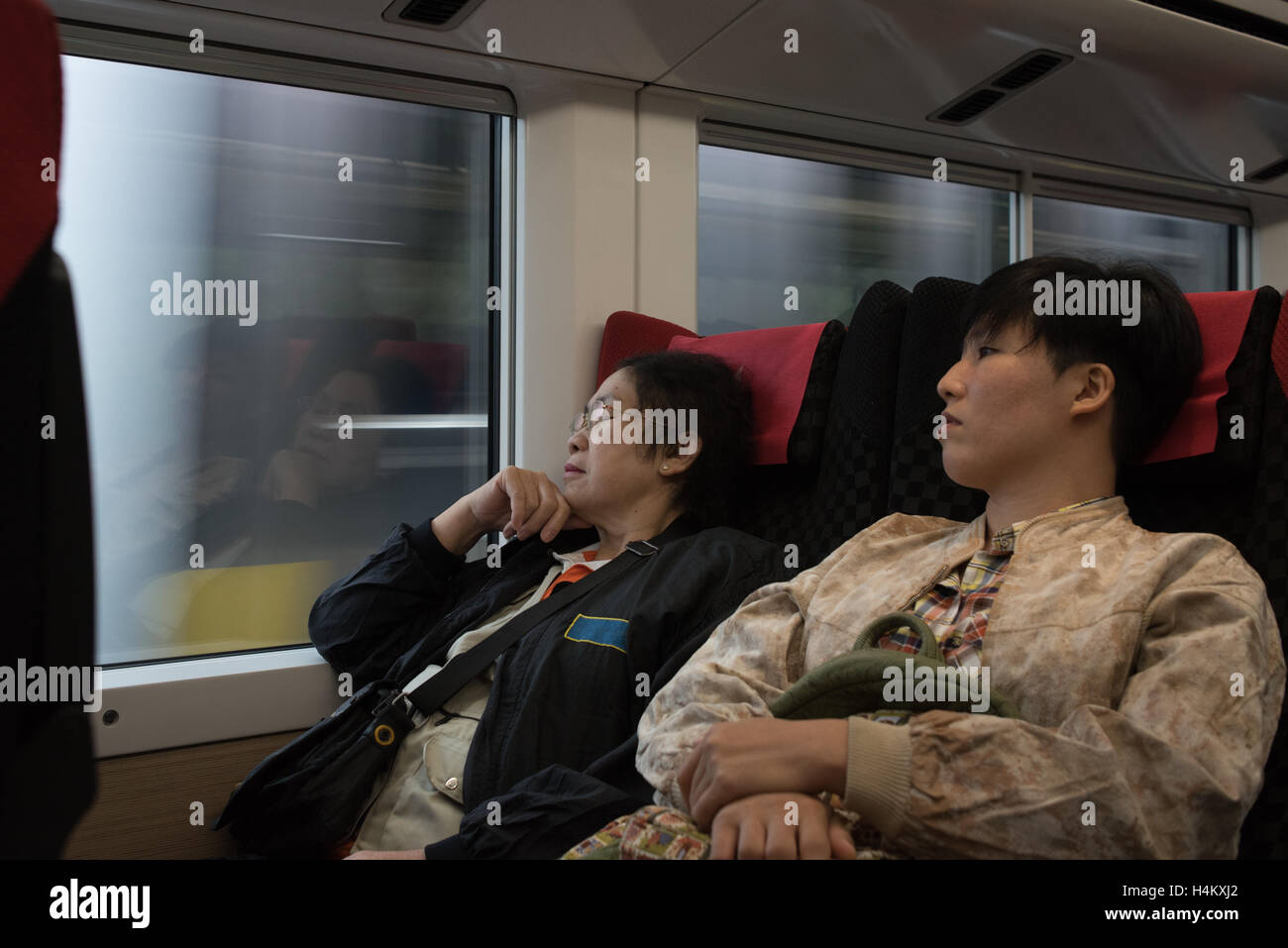 Two of ladies Asian woman sit in train,one sleep,one look through window. Stock Photo