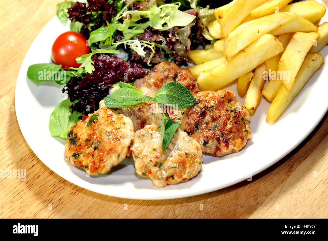 Grilled Chicken Meatball served with fries and salad Stock Photo