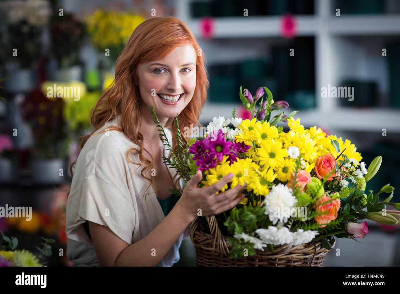Happy female florist holding basket of flowers Stock Photo