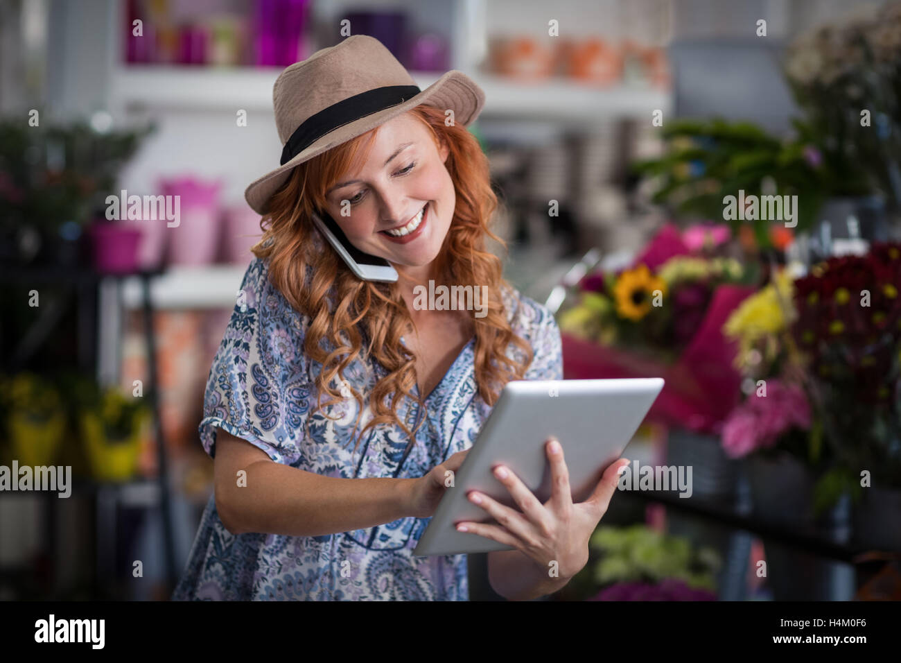 Female florist talking on mobile phone while using digital tablet Stock Photo