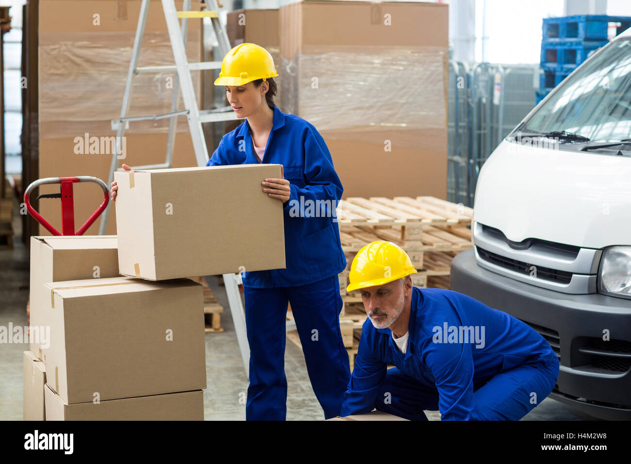 Delivery workers unloading cardboard boxes from pallet jack Stock Photo