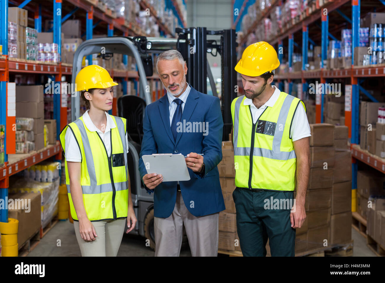 Warehouse manager and co-workers discussing over clipboard Stock Photo