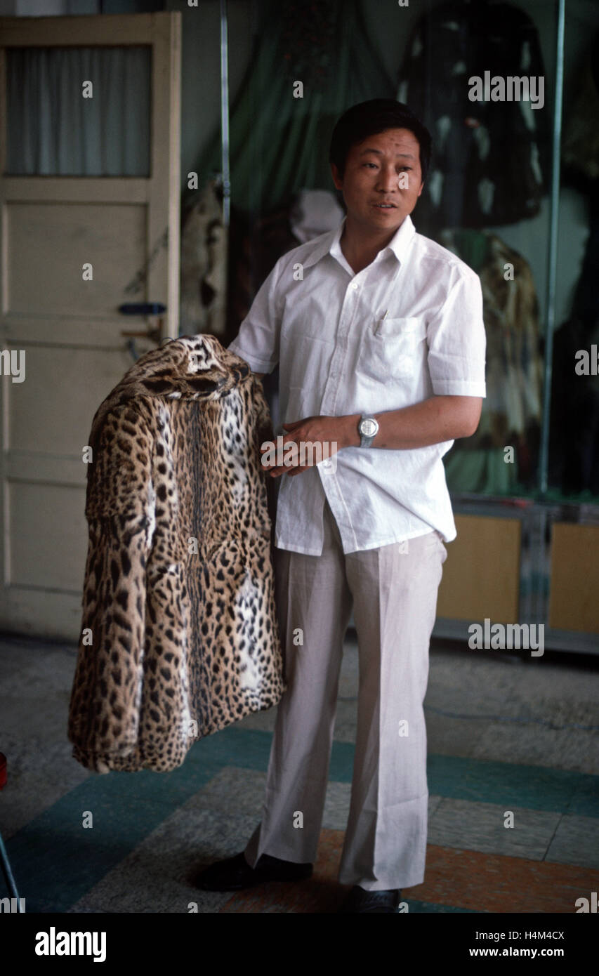 Owner of Harbin Fur Factory holding fur coat made from endangered animal skin, Heliongjiang Province, China Stock Photo