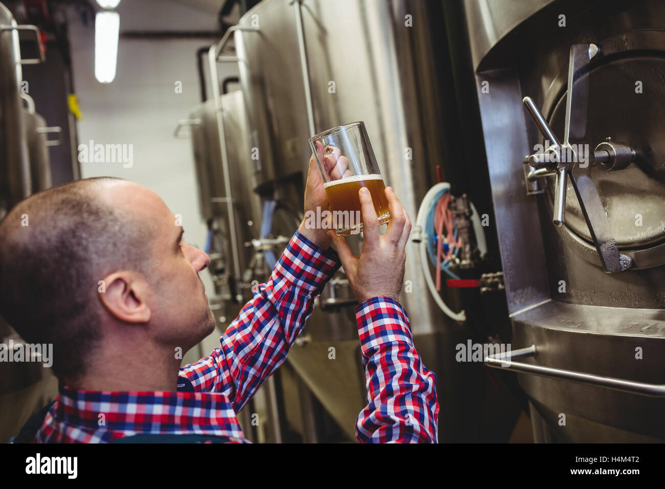 Brewery worker inspecting beer in glass Stock Photo