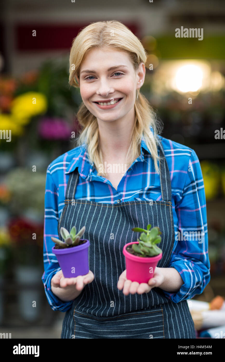 Female florist holding plant pot in flower shop Stock Photo