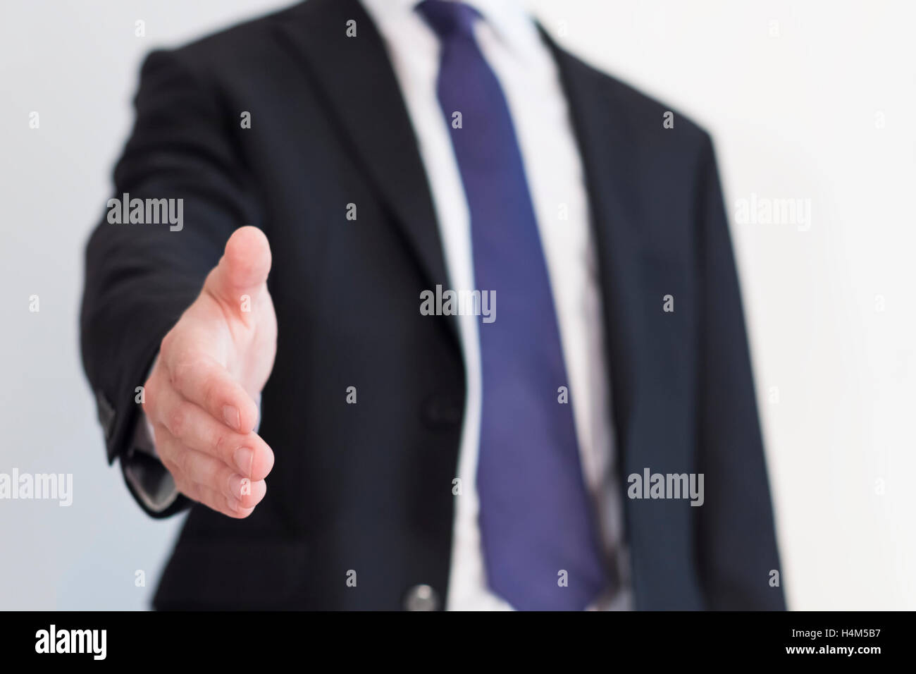 Businessman with white shirt and blue tie ready to handshake or seal a deal with open hand welcoming you Stock Photo