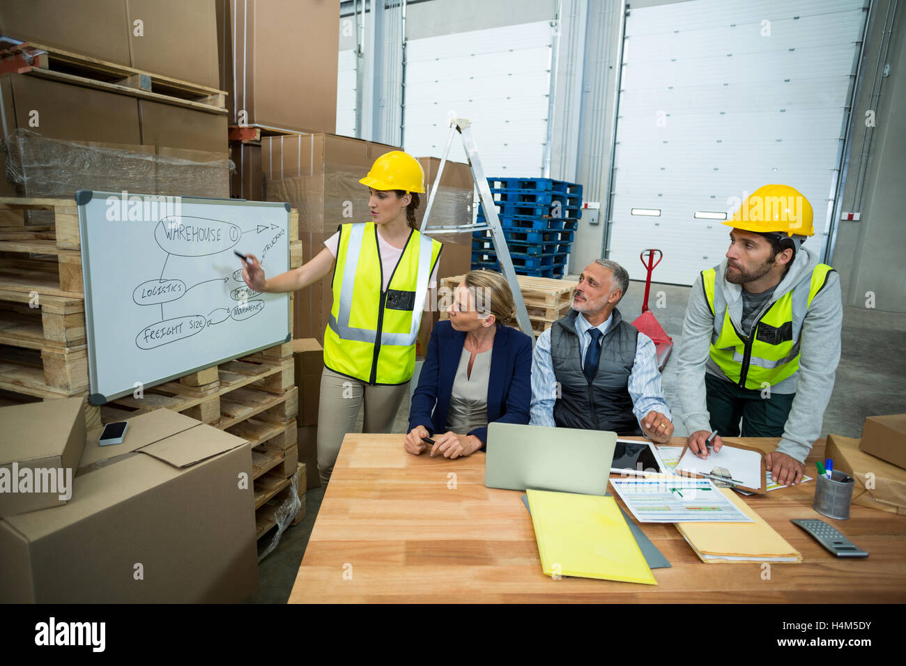 Warehouse workers and managers discussing plan on whiteboard Stock Photo