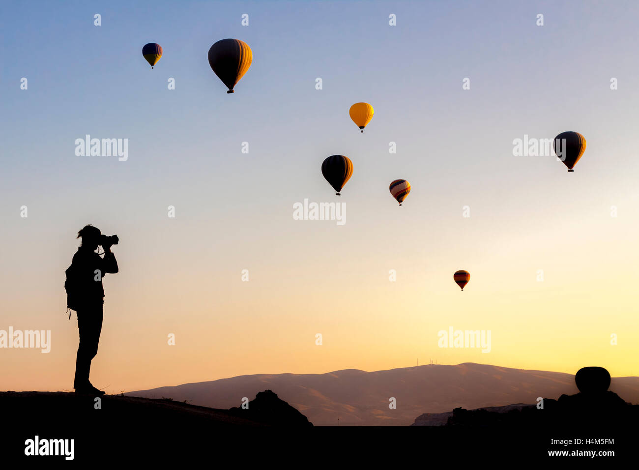 Female tourist taking photos of hot air balloon in Cappadocia, Anatolia, Turkey Stock Photo