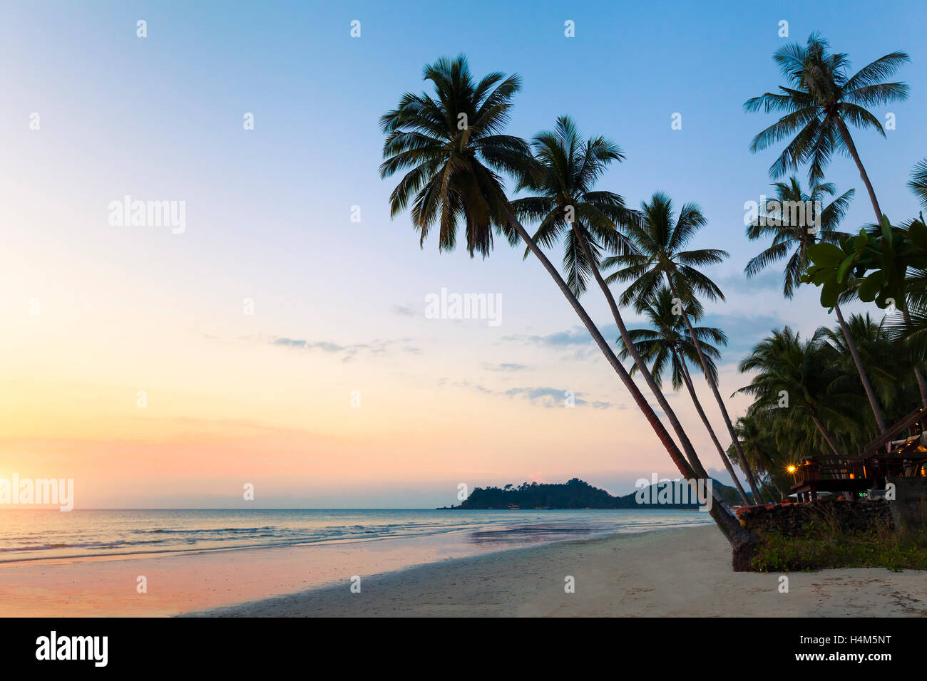 Beautiful tropical beach landscape, palm trees, sea, resort and sunset Stock Photo