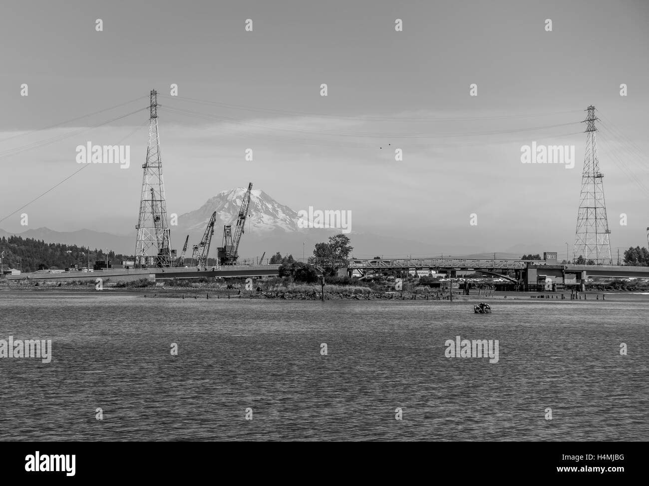 Majestic Mount Rainier is in the distance behind power lines and equipment. Black and white image. Stock Photo