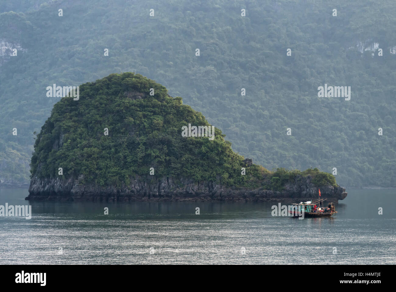 Fishing boat in Ha Long Bay against whale shaped islet Stock Photo