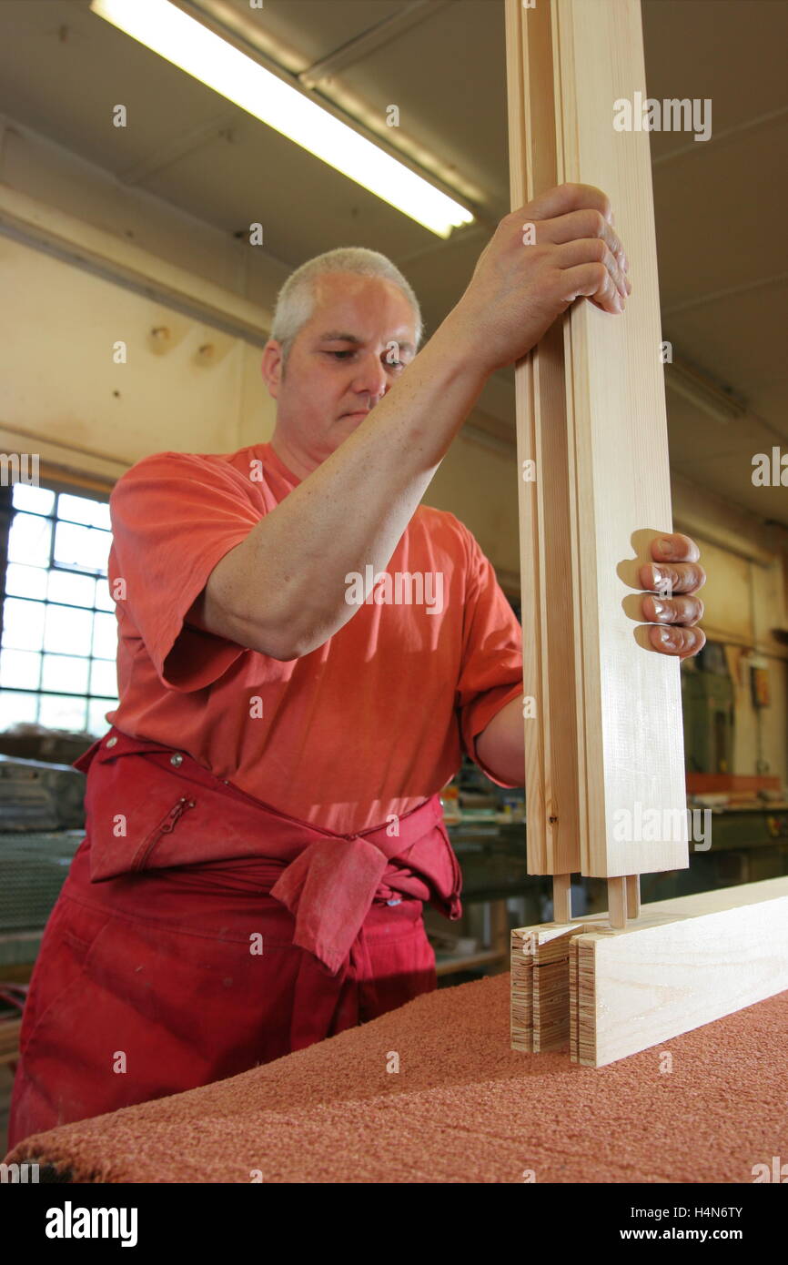 A worker in a joinery assembles a large window frame from